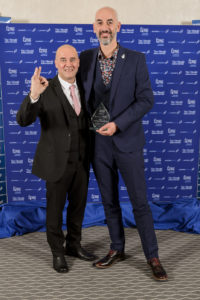 The two representatives of Jog Con, in suits, holding their award